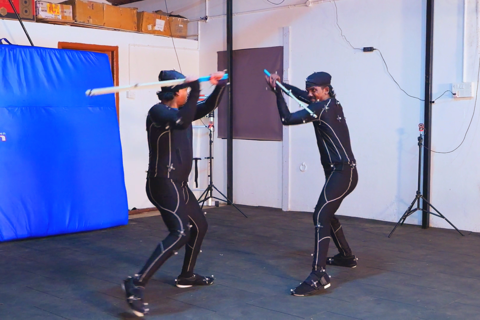 Two actors performing a staged sword fight in mocap suits