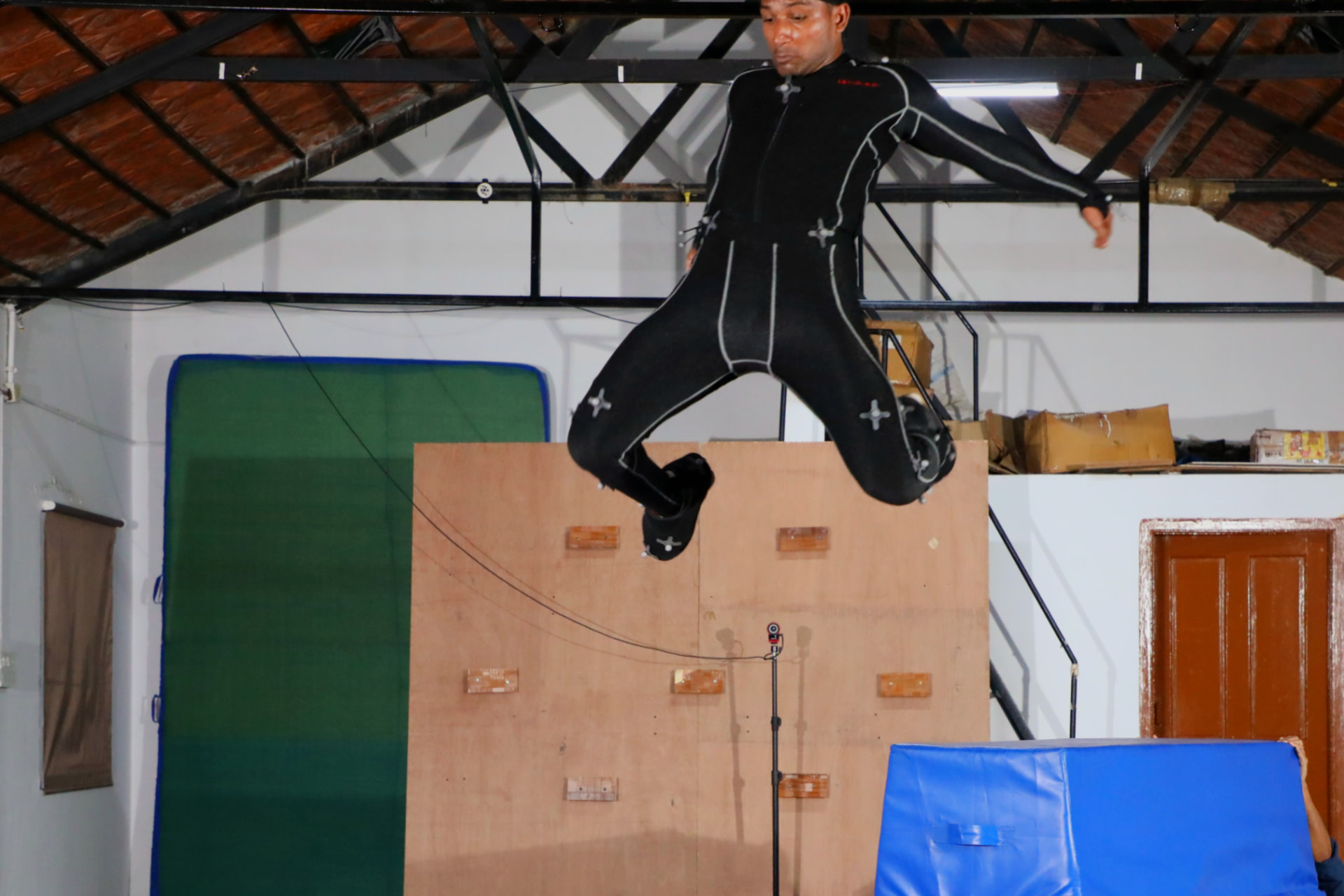 Performer mid-air leaping from a climbing wall on the mocap stage